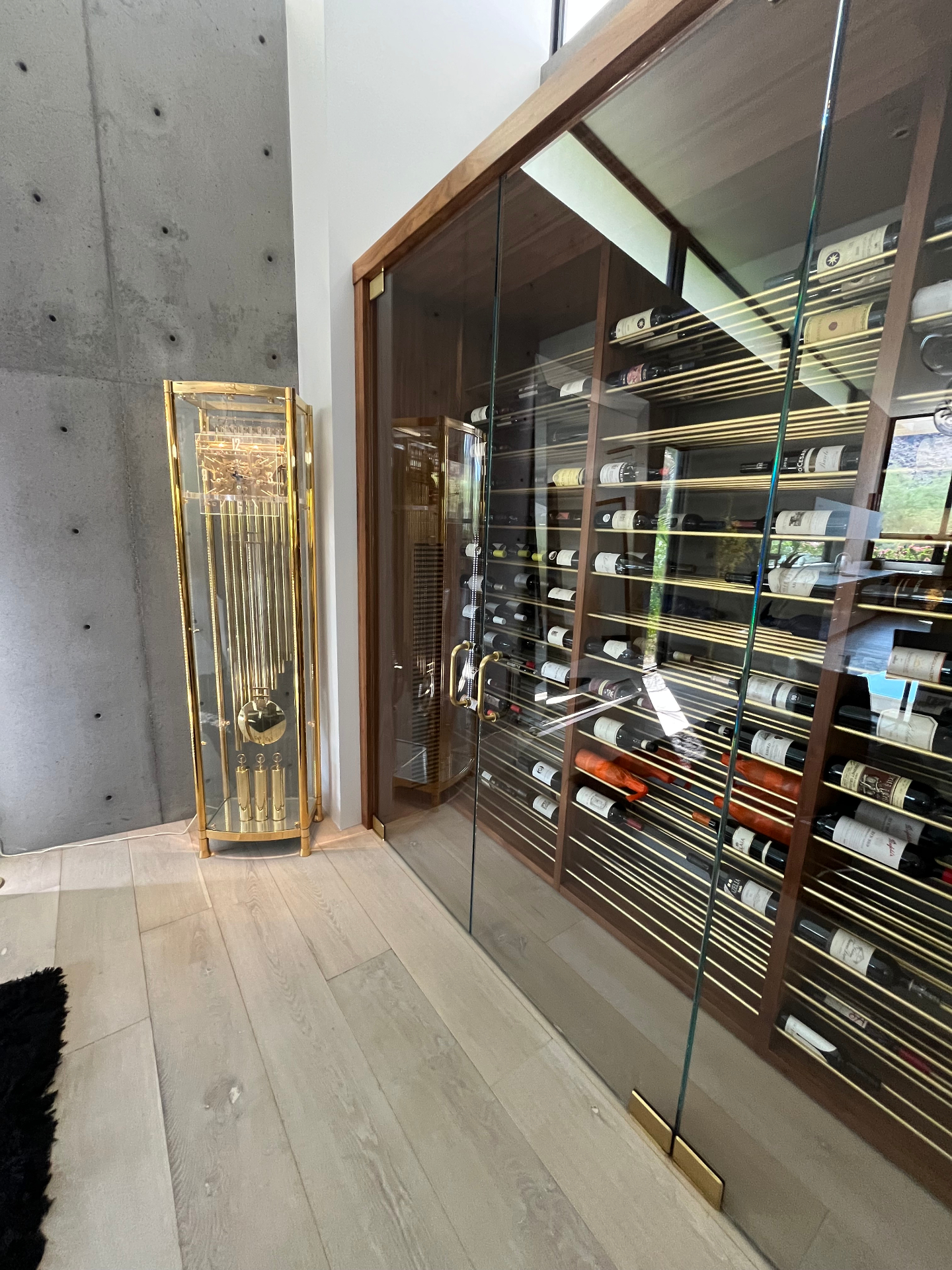 Custom glass-enclosed walk-in wine wall with brass racking and a climate-controlled collection installed in an Arizona home