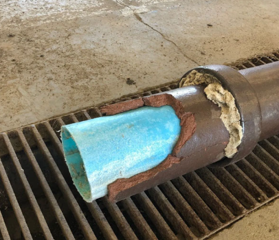 Cutaway view of a cast iron pipe showing the cured CIPP liner bonded inside the original pipe wall.