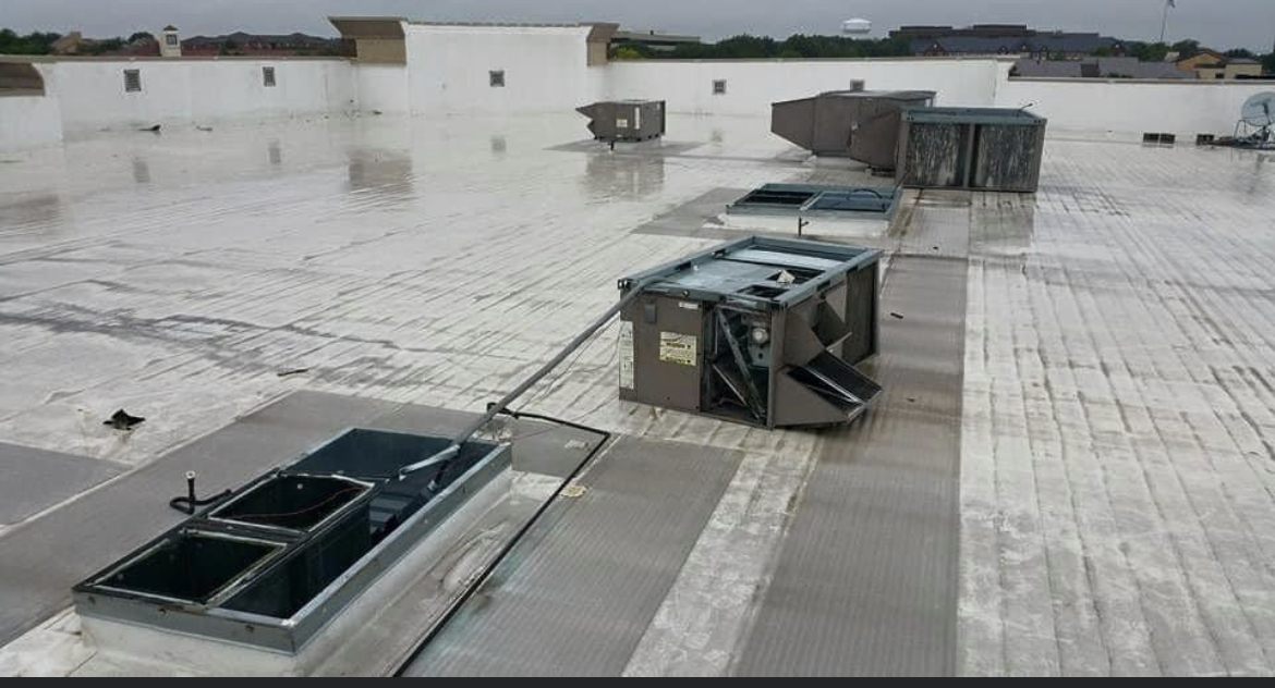 Rooftop HVAC package units and open access hatches on a commercial roof in Arizona after a monsoon rain
